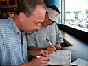 P1010264.jpg: Sean & Matt doing seek-n-finds in bar at Charlotte, NC Airport